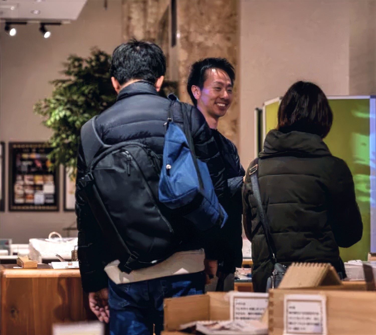 An Okawa Furniture staff member smiles while speaking with two customers in a store.